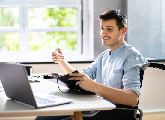 Male student using assistive technology looking at a computer smiling