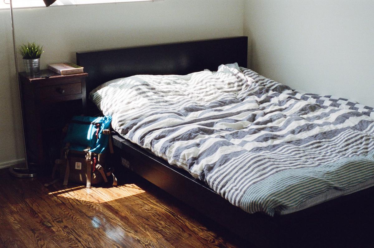 Bed with a backpack on the floor next to it