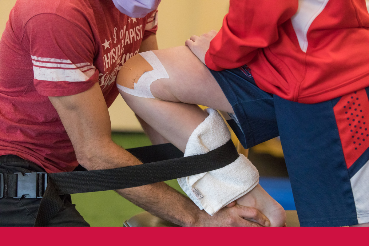 Man performing physiotherapy and injury recovery on a teenager with a knee injury