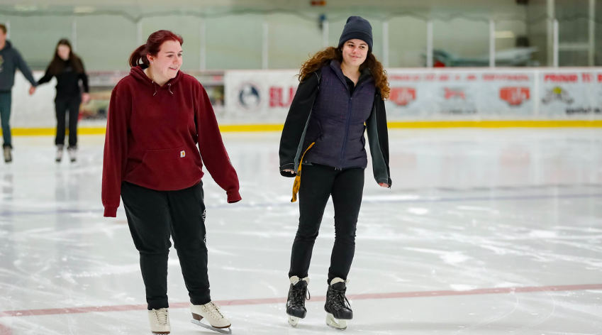 Two women skating on an indoor rink