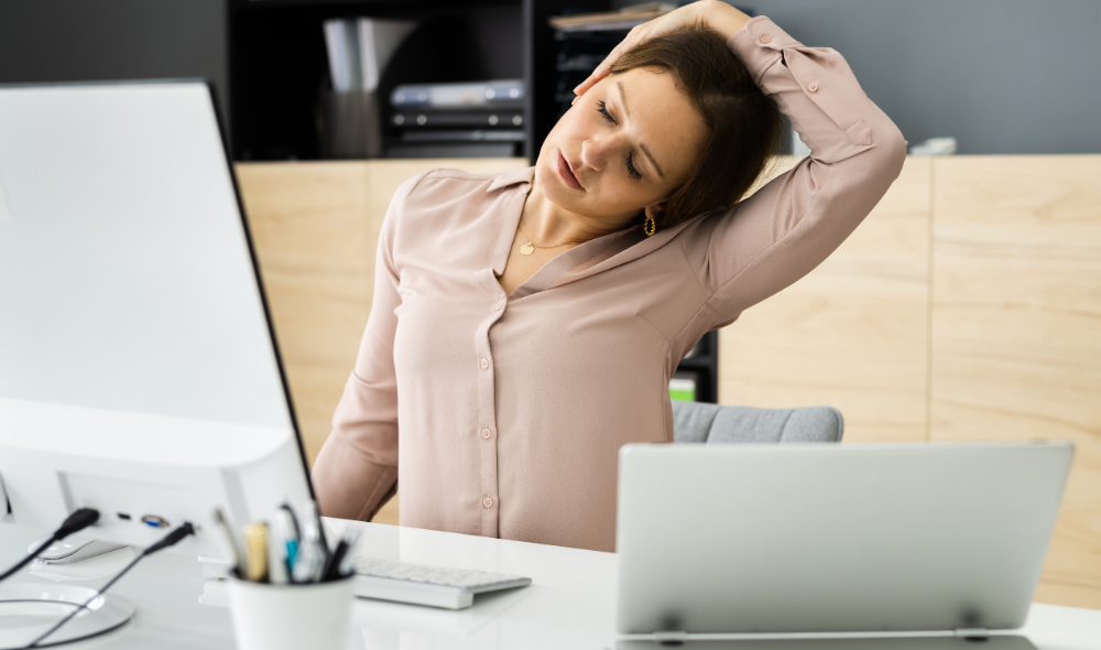 Woman taking a Movement Break at her desk stretching her neck