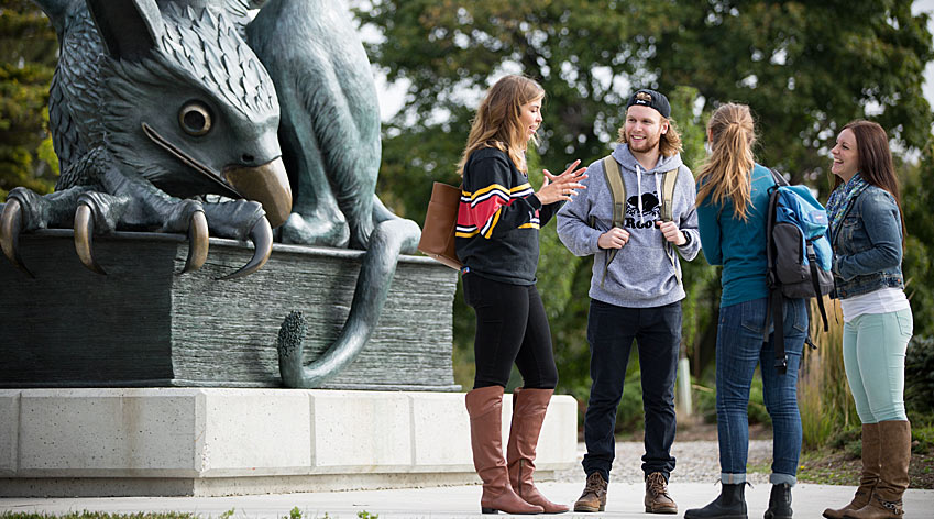 Students standing in front of the gryphon statue